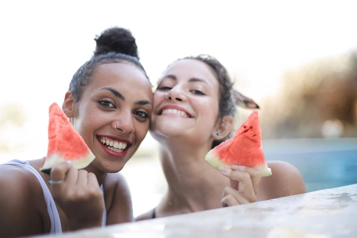 2 Freundinnen sind im Pool und essen eine leckere Wassermelone und freuen sich 2 Freundinnen sind im Pool und essen eine leckere Wassermelone und freuen sich